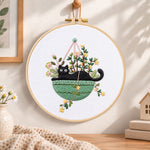 Cat in green hanging pot embroidery hoop wall art displayed as warm and cozy handmade home decor