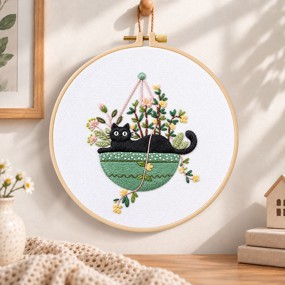 Cat in green hanging pot embroidery hoop wall art displayed as warm and cozy handmade home decor