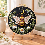Celestial bee with daisies embroidery kit finished hoop displayed on a wooden stand as cozy tabletop decor