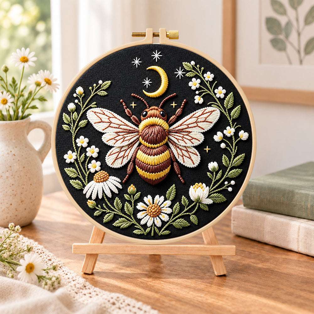 Celestial bee with daisies embroidery kit finished hoop displayed on a wooden stand as cozy tabletop decor