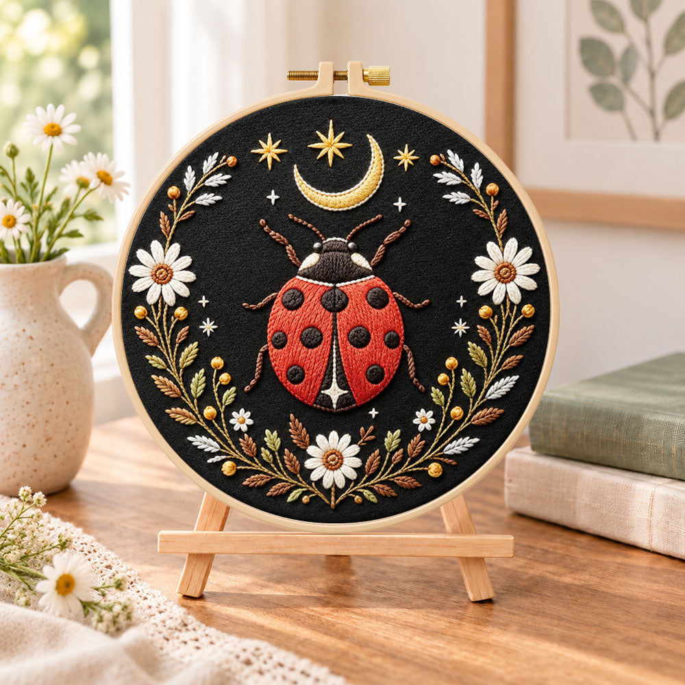 Celestial ladybug embroidery kit finished hoop displayed on a wooden stand as cozy tabletop decor