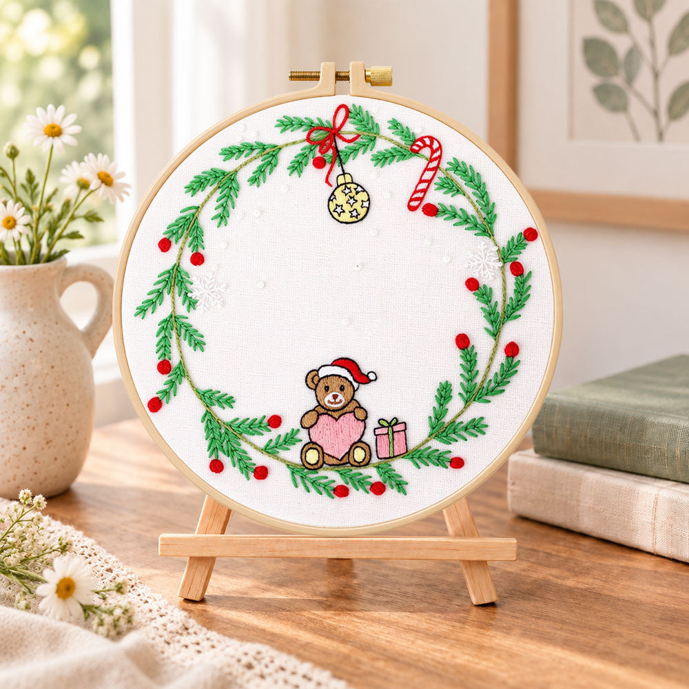 Christmas bear wreath embroidery kit finished hoop displayed on a wooden stand as cozy tabletop decor