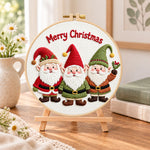 Christmas gnomes trio embroidery kit finished hoop displayed on a wooden stand as cozy tabletop decor