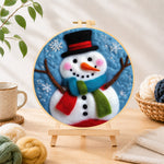 Finished christmas snowman with striped scarf needle felting displayed on a wooden easel