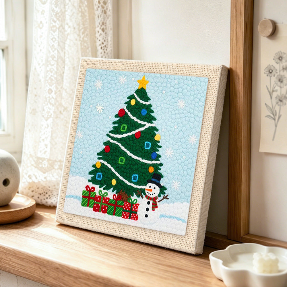 Christmas tree and snowman punch needle artwork displayed on a table