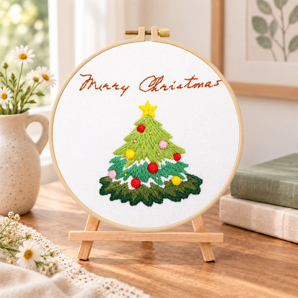 Christmas tree greeting embroidery kit finished hoop displayed on a wooden stand as cozy tabletop decor