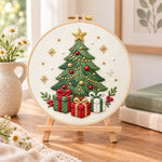 Christmas tree with gifts embroidery kit finished hoop displayed on a wooden stand as cozy tabletop decor