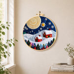 Christmas village with big moon needle felt wall art displayed in a bright home interior