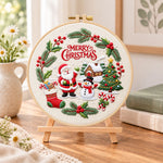 Christmas wreath scene embroidery kit finished hoop displayed on a wooden stand as cozy tabletop decor