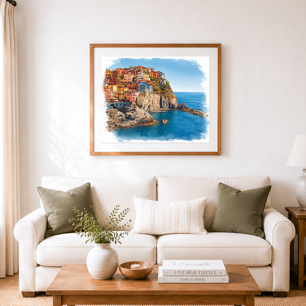 Finished cliffside coastal village cross stitch artwork displayed as home decor