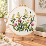Clover and daisy floral embroidery kit finished hoop displayed on a wooden stand as cozy tabletop decor