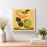 Finished cocktail with green leaves and lime artwork displayed on a wall