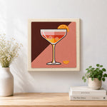 Finished cocktail with ice and orange slice artwork displayed on a wall