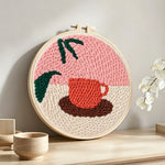 Coffee cup and leaf punch needle artwork displayed on a table