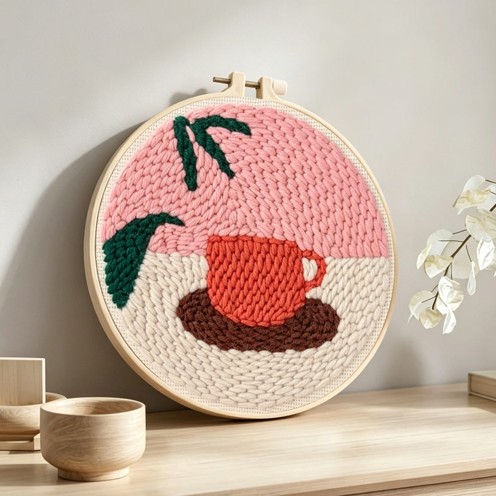 Coffee cup and leaf punch needle artwork displayed on a table