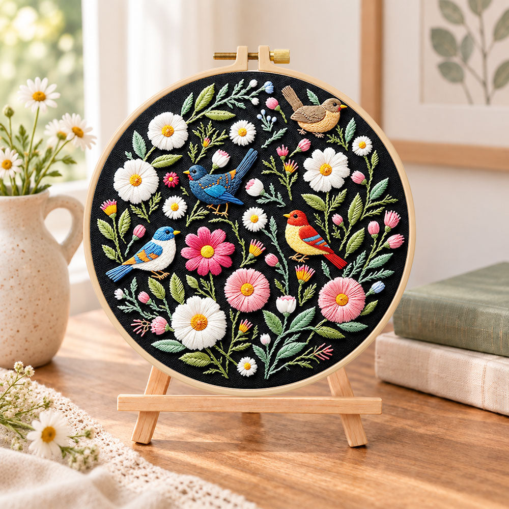 Colorful birds and wildflowers embroidery kit finished hoop displayed on a wooden stand as cozy tabletop decor