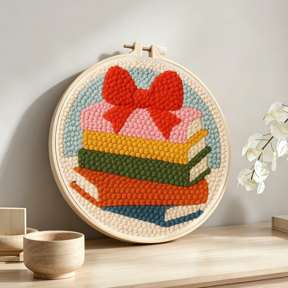 Colorful book stack with bow punch needle artwork displayed on a table
