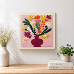 Finished colorful bouquet in burgundy vase artwork displayed on a wall