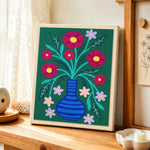Colorful flowers in striped blue vase punch needle artwork displayed on a table