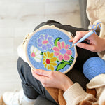 Creating handmade colorful flowers on blue-background punch needle artwork
