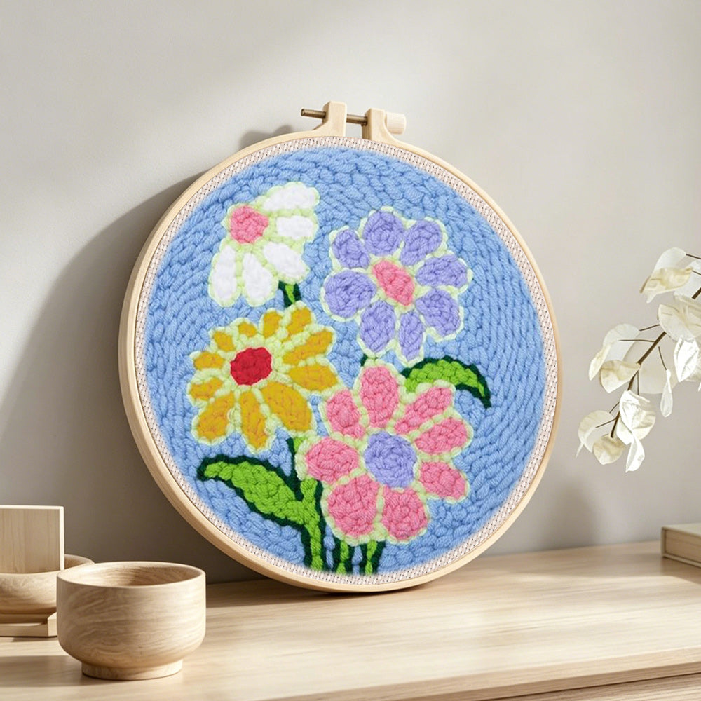 Colorful flowers on blue-background punch needle artwork displayed on a table
