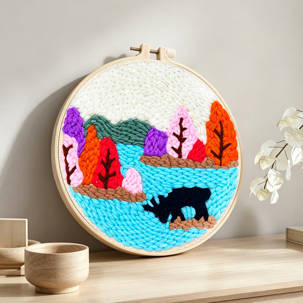 Colorful forest above a lake punch needle artwork displayed on a table