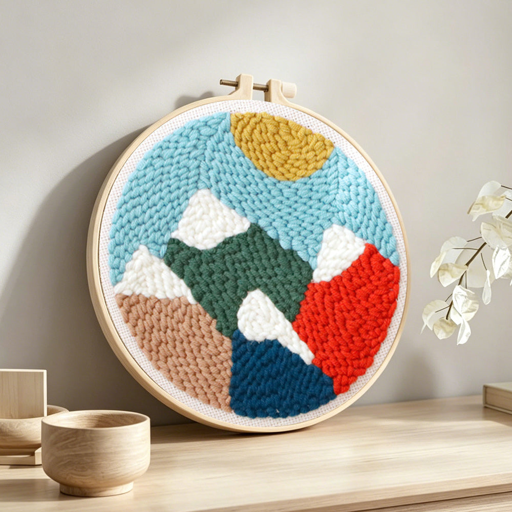 Colorful mountain landscape punch needle artwork displayed on a table