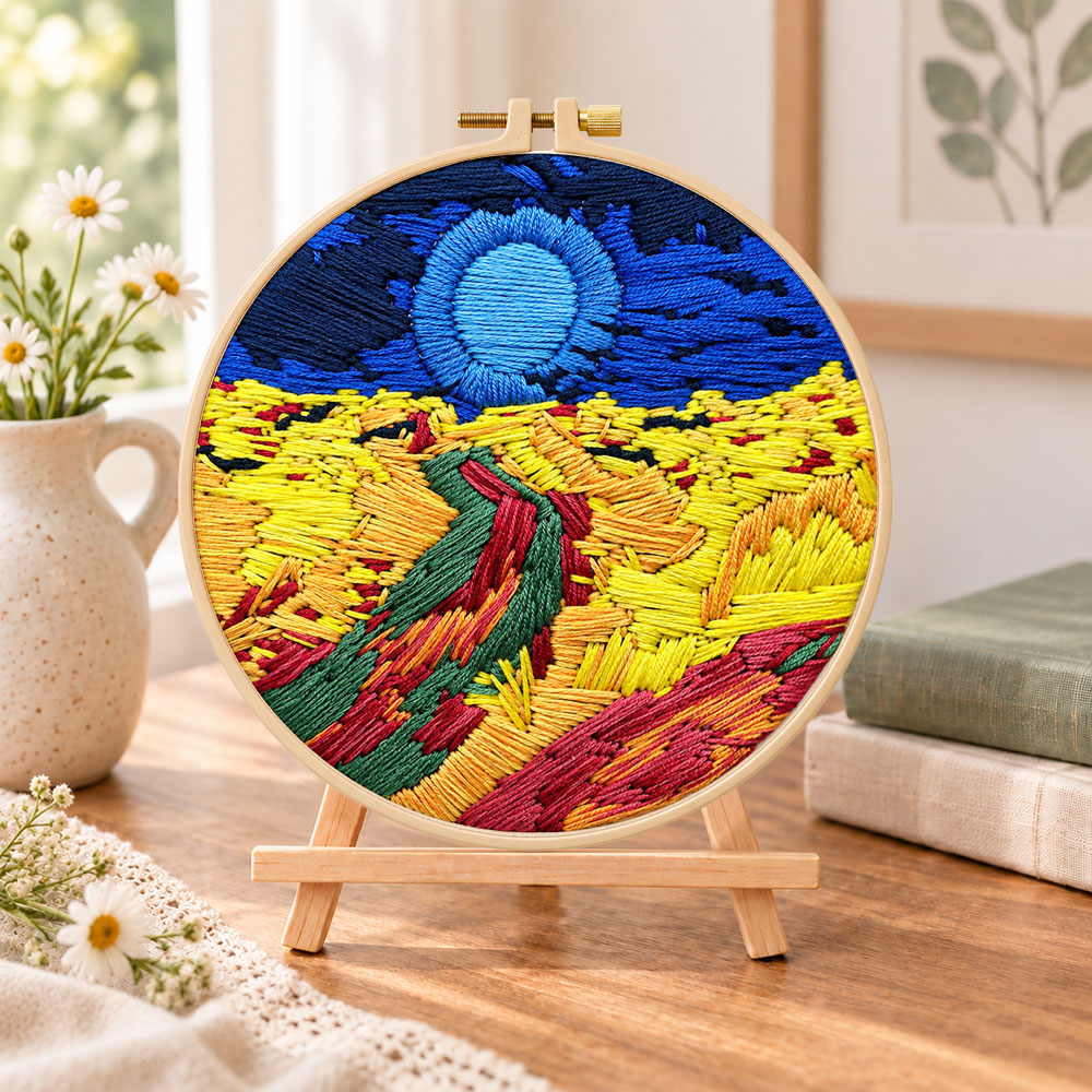 Colorful mountain sunset embroidery kit finished hoop displayed on a wooden stand as cozy tabletop decor