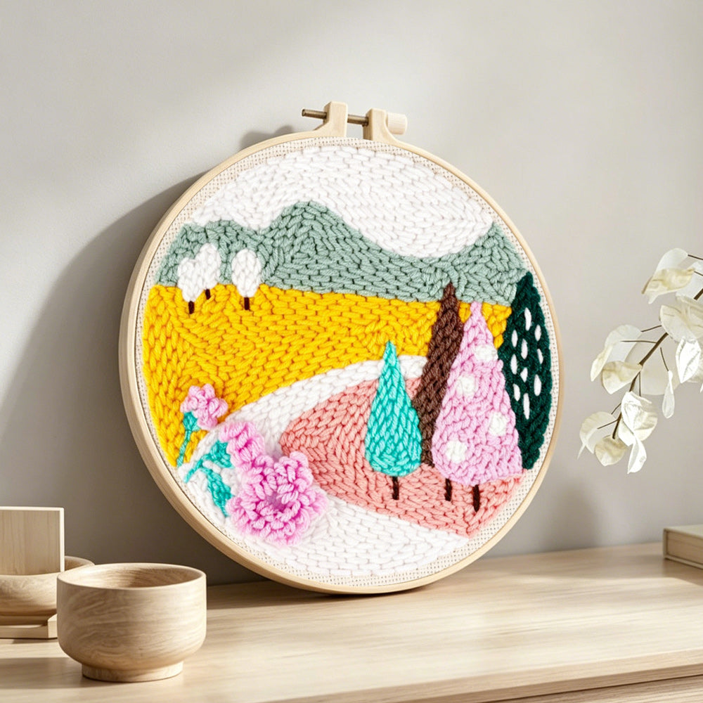 Colorful mountains and trees punch needle artwork displayed on a table