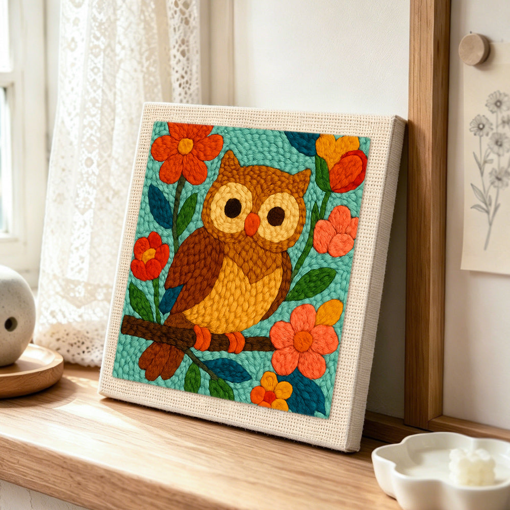 Colorful owl on flowering branch punch needle artwork displayed on a table