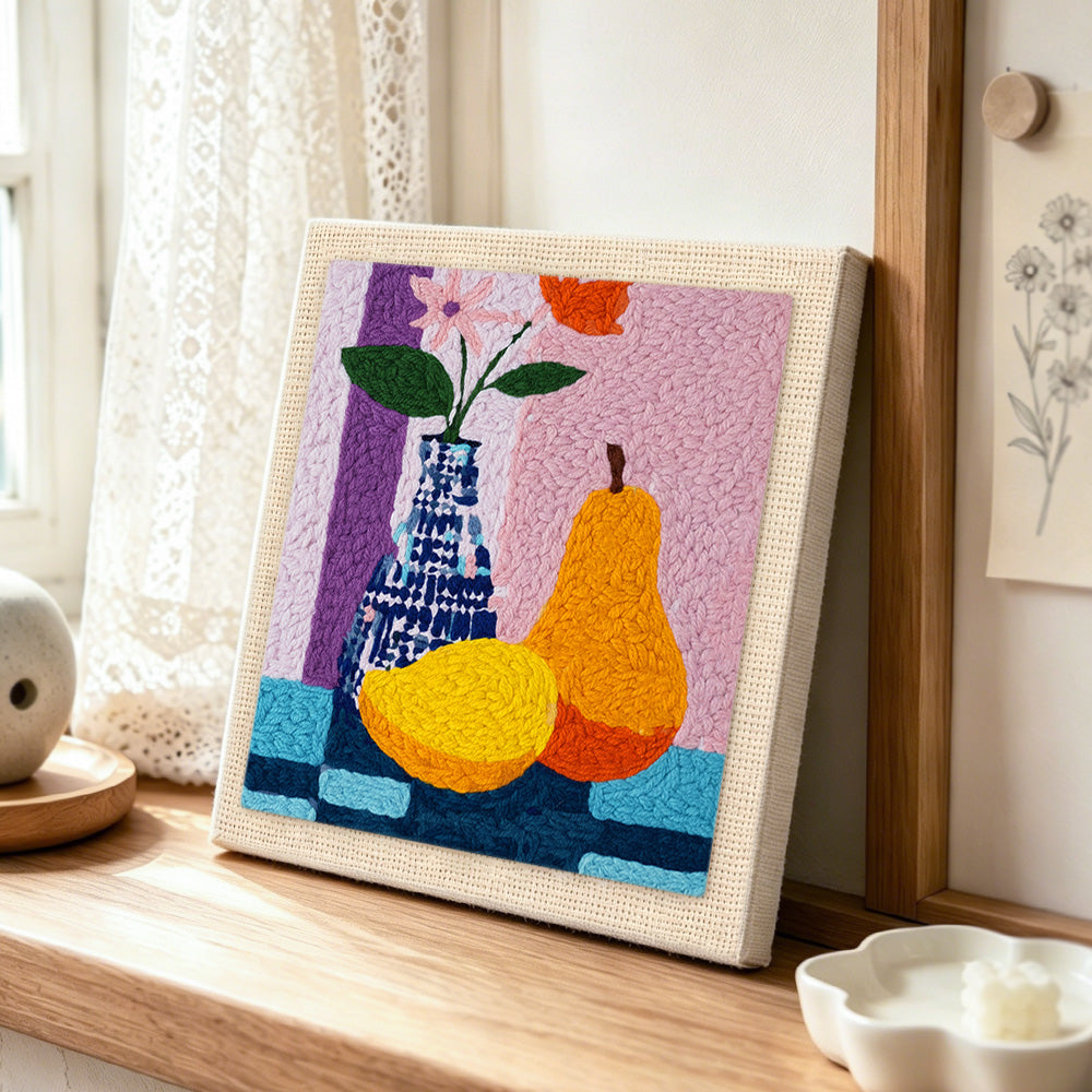 Colorful pear and vase still life punch needle artwork displayed on a table