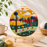 Finished colorful round trees on whimsical hills needle felting displayed on a wooden easel