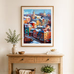 Finished colorful snowy european town cross stitch artwork displayed as home decor