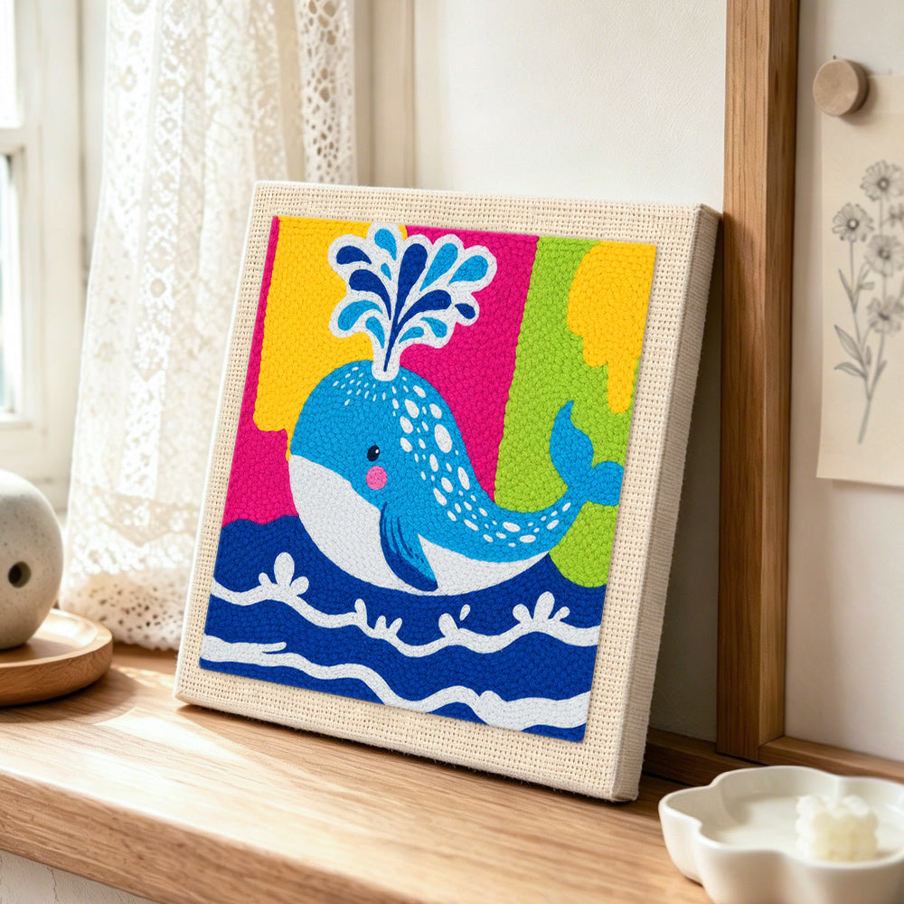 Colorful spouting whale punch needle artwork displayed on a table