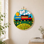 Colorful train on grass needle felt wall art displayed in a bright home interior
