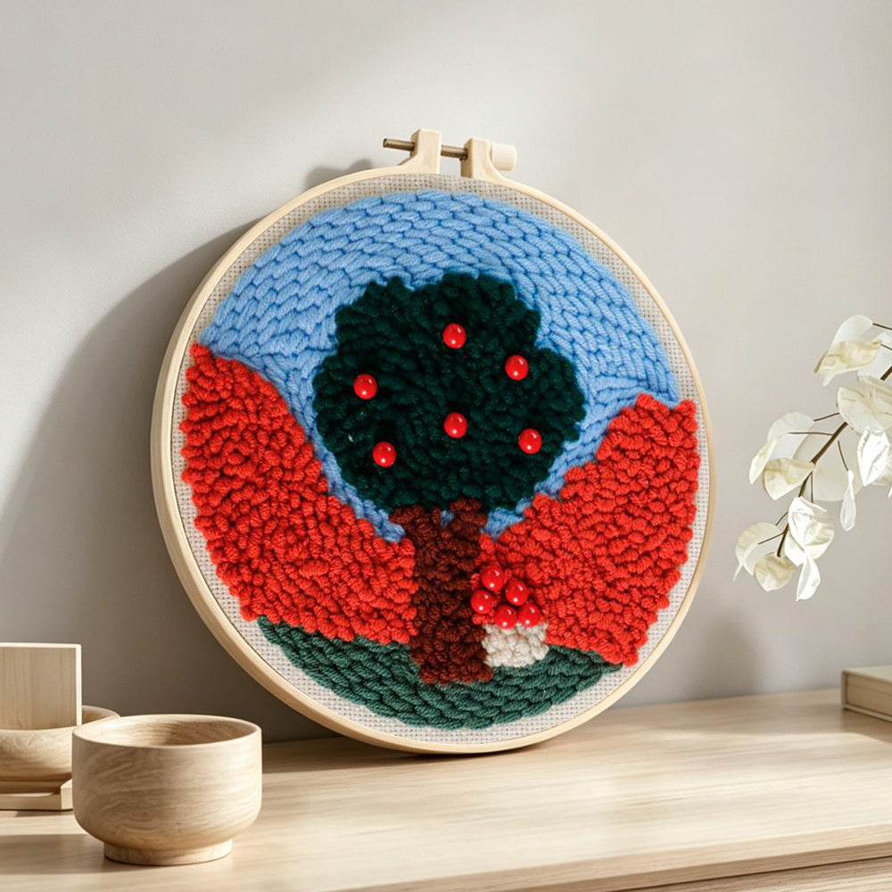 Colorful tree with red beads punch needle artwork displayed on a table