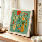 Colorful wildflowers in the glass bottles punch needle artwork displayed on a table