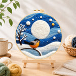 Finished cosy winter bird under the full moon needle felting displayed on a wooden easel