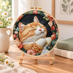 Cozy napping orange cat embroidery kit finished hoop displayed on a wooden stand as cozy tabletop decor