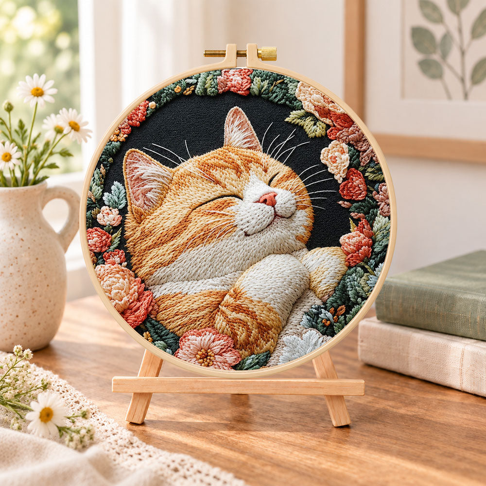 Cozy napping orange cat embroidery kit finished hoop displayed on a wooden stand as cozy tabletop decor