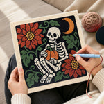 Creating handmade cozy skeleton holding pumpkin punch needle artwork