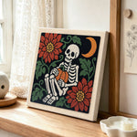 Cozy skeleton holding pumpkin punch needle artwork displayed on a table