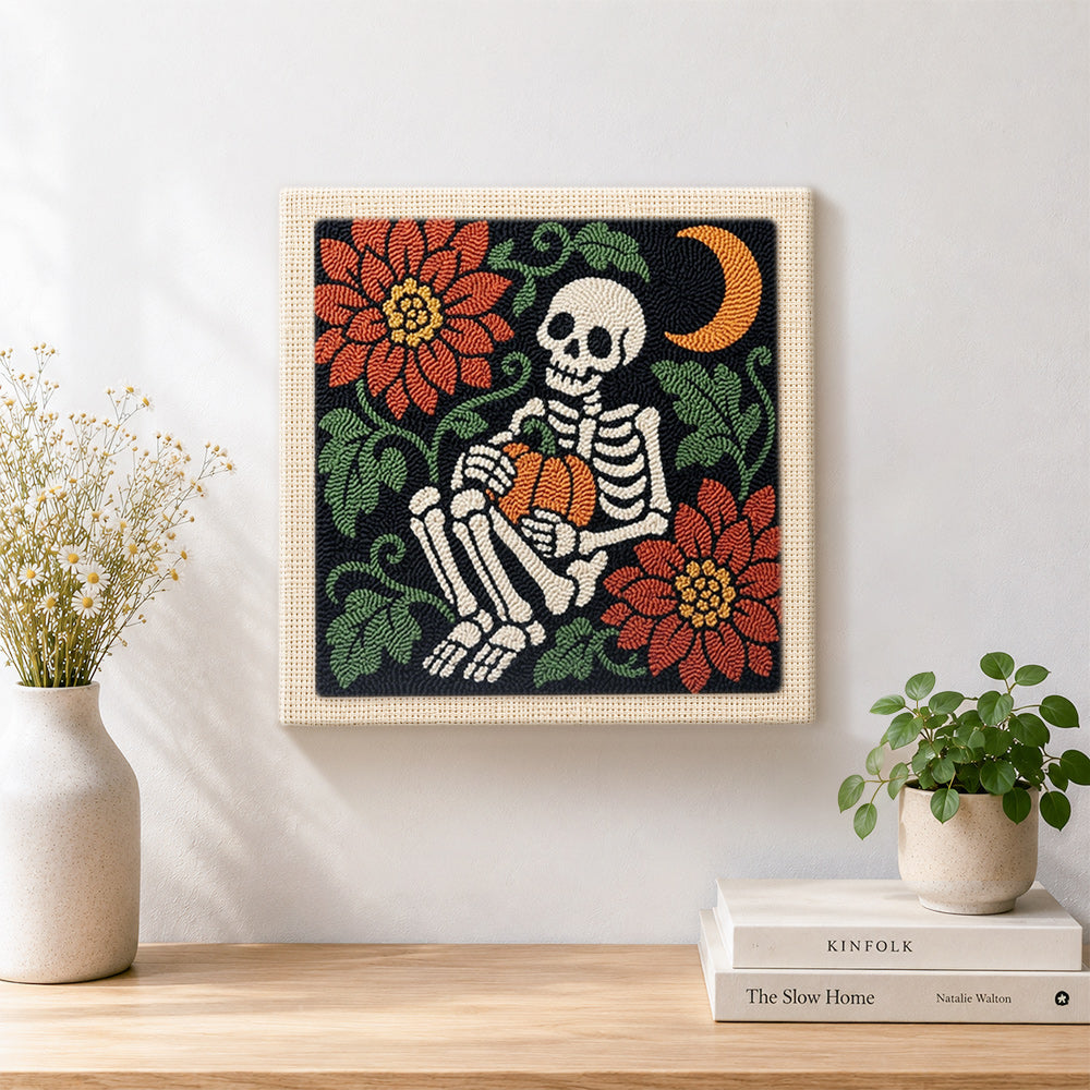 Finished cozy skeleton holding pumpkin artwork displayed on a wall