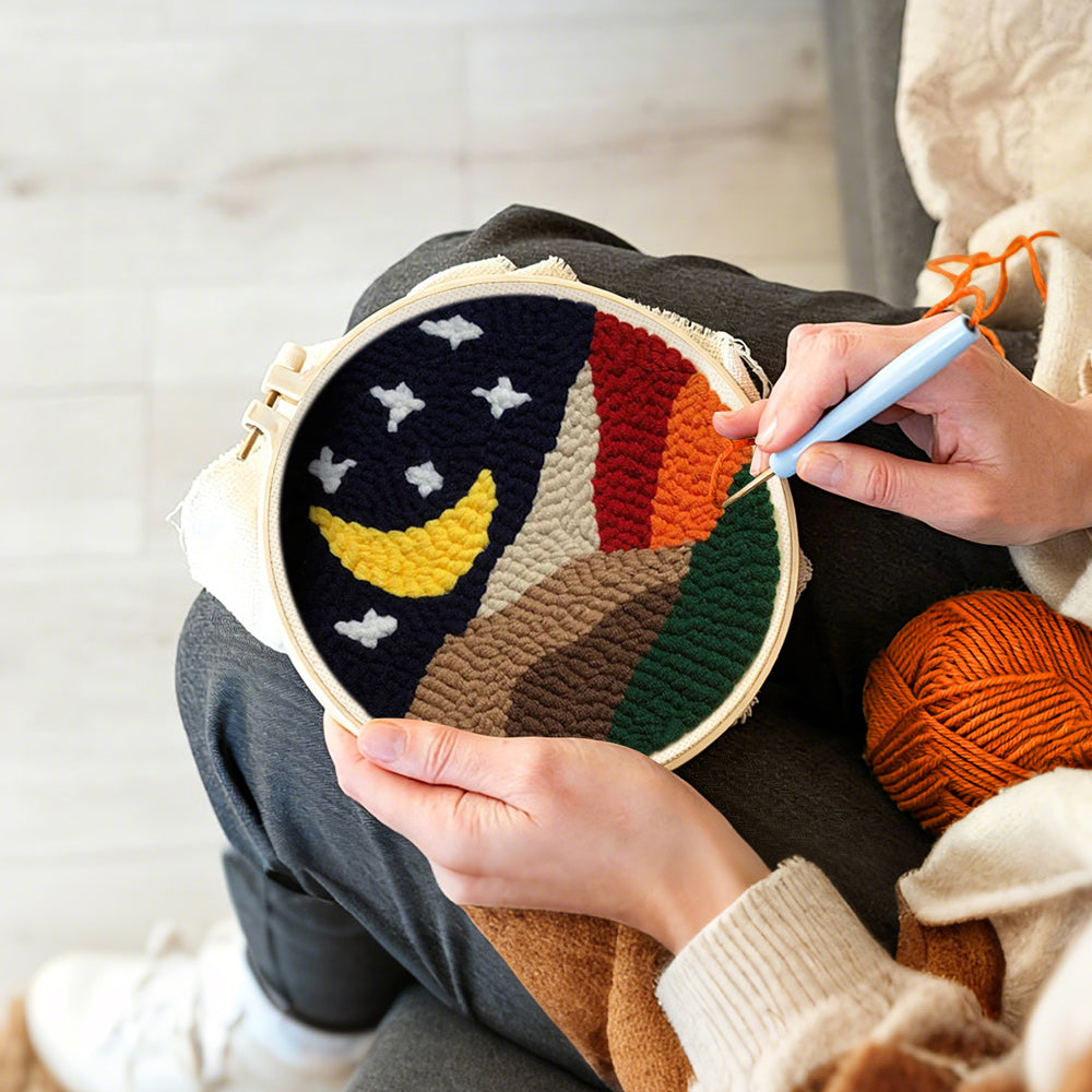Creating handmade crescent moon and white stars above the colorful mountains punch needle artwork