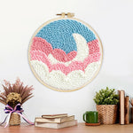 Finished crescent moon over pink and white clouds artwork displayed on a wall