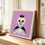 Crown skeleton punch needle artwork displayed on a table