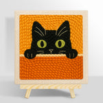 Curious black cat peeking over punch needle kit for beginners
