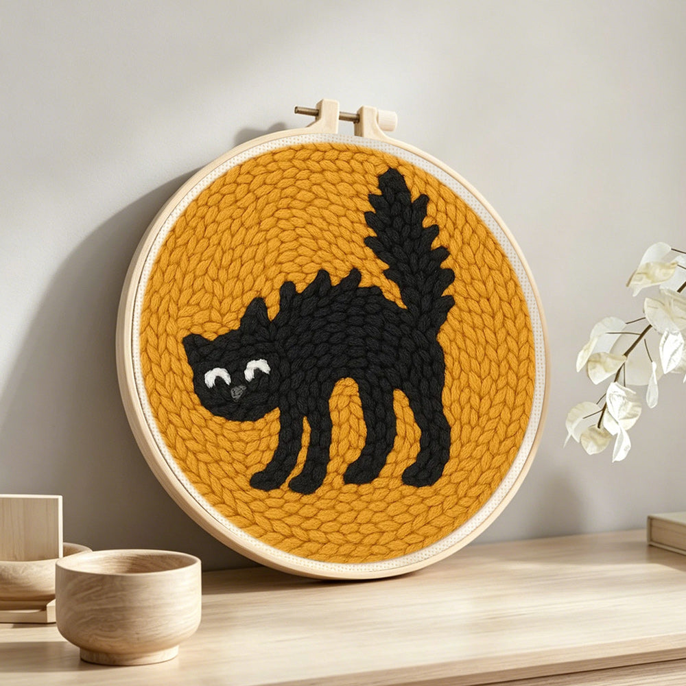 Curled black cat punch needle artwork displayed on a table