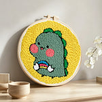 Cute baby dinosaur punch needle artwork displayed on a table