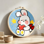 Cute bunny holding heart punch needle artwork displayed on a table